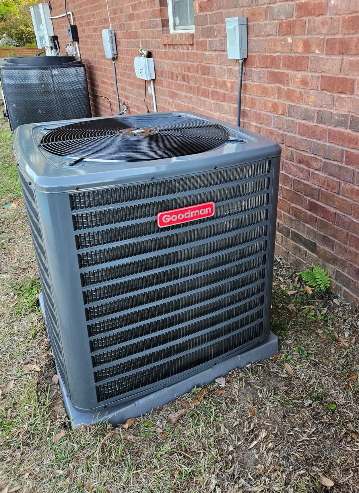 Newly installed outdoor air conditioning condenser beside a brick home